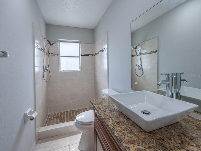 full bath featuring a tile shower, toilet, vanity, and tile patterned floors