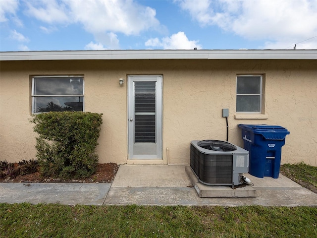entrance to property with cooling unit and stucco siding