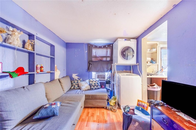 living area with cooling unit, stacked washing maching and dryer, and wood finished floors