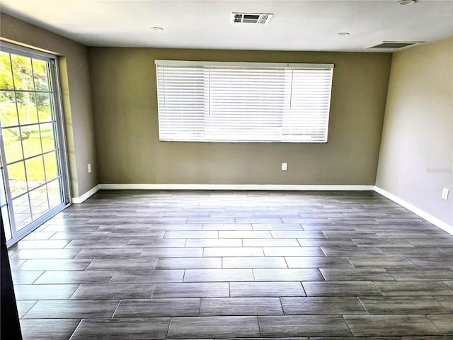 empty room with baseboards, plenty of natural light, and wood finish floors