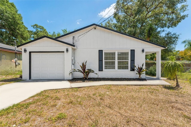 ranch-style home featuring an attached garage, concrete driveway, fence, and a front yard