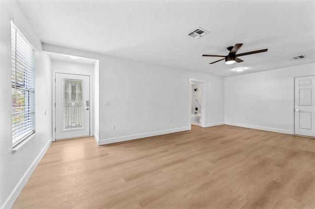 spare room featuring a textured ceiling, visible vents, a ceiling fan, baseboards, and light wood-style floors