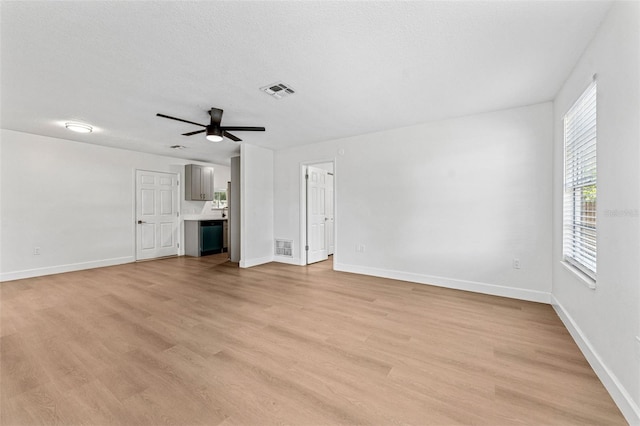 unfurnished living room with visible vents, light wood-style flooring, baseboards, and ceiling fan