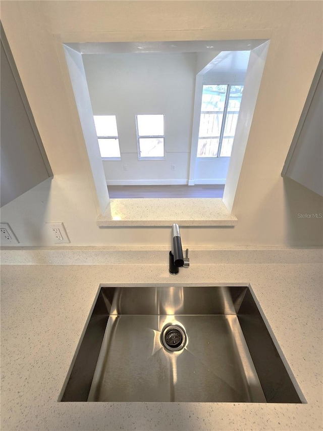 interior details featuring light stone counters and a sink