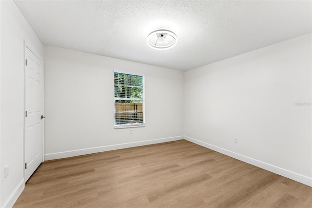 interior space featuring light wood finished floors, a textured ceiling, and baseboards