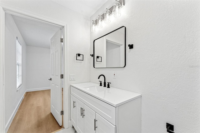 bathroom with baseboards, vanity, and wood finished floors