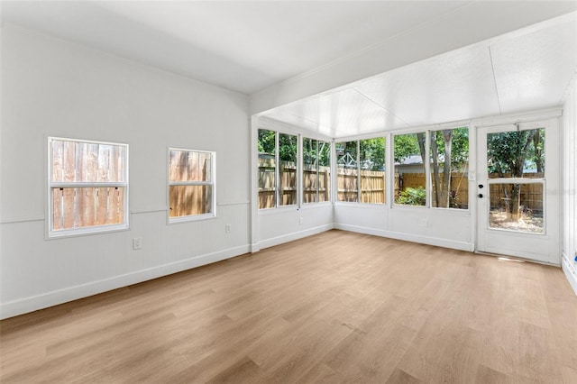 unfurnished sunroom with baseboards, a healthy amount of sunlight, and wood finished floors