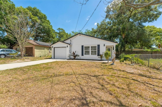view of front of property with concrete driveway, a garage, a front lawn, and fence