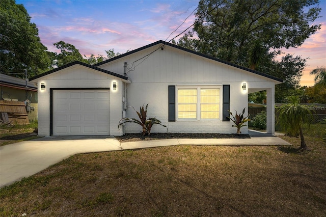 ranch-style house with an attached garage, concrete driveway, fence, and a lawn