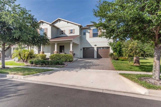 traditional home with decorative driveway, a garage, a front lawn, and stucco siding