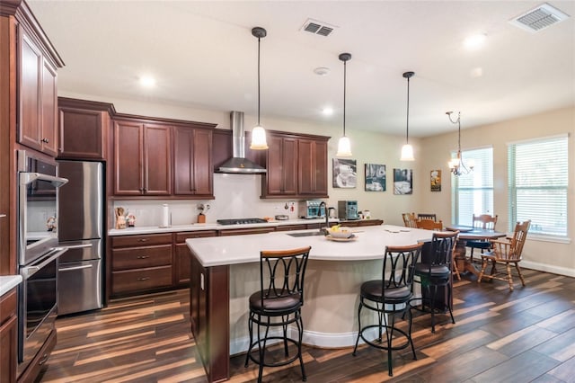 kitchen featuring light countertops, stainless steel double oven, dark wood-style floors, and wall chimney exhaust hood
