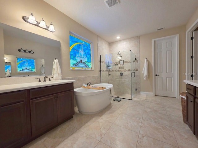 bathroom featuring visible vents, vanity, a soaking tub, and a shower stall