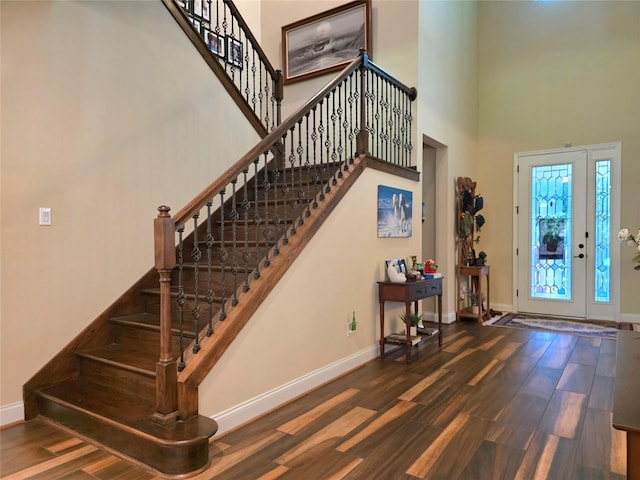 foyer with baseboards, a towering ceiling, wood finished floors, and stairway