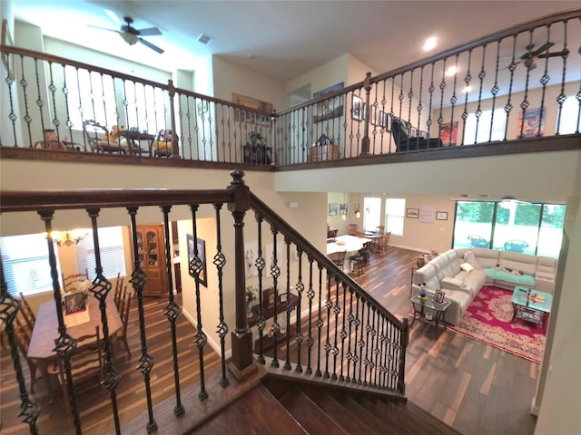 staircase with a high ceiling, a ceiling fan, wood finished floors, and visible vents