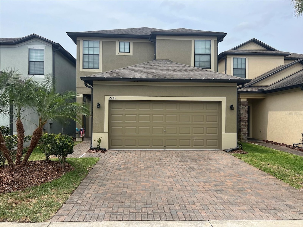 view of front of house with stucco siding, an attached garage, and decorative driveway