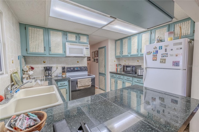 kitchen featuring tasteful backsplash, white appliances, a sink, tile countertops, and a peninsula