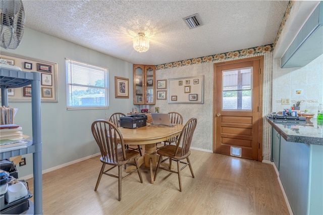 dining room with a textured ceiling, visible vents, plenty of natural light, and light wood finished floors