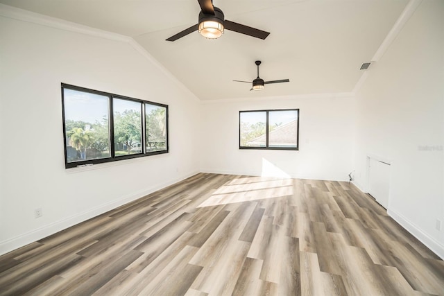 unfurnished room featuring ceiling fan, wood finished floors, vaulted ceiling, baseboards, and ornamental molding