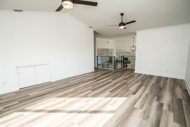 unfurnished living room featuring ceiling fan, lofted ceiling, wood finished floors, ornamental molding, and baseboards
