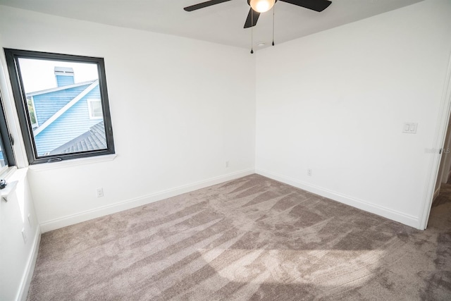 carpeted empty room featuring ceiling fan and baseboards