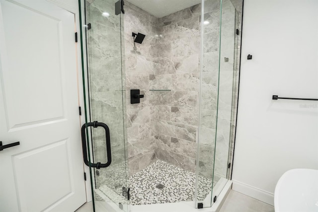 full bathroom with a shower stall and baseboards