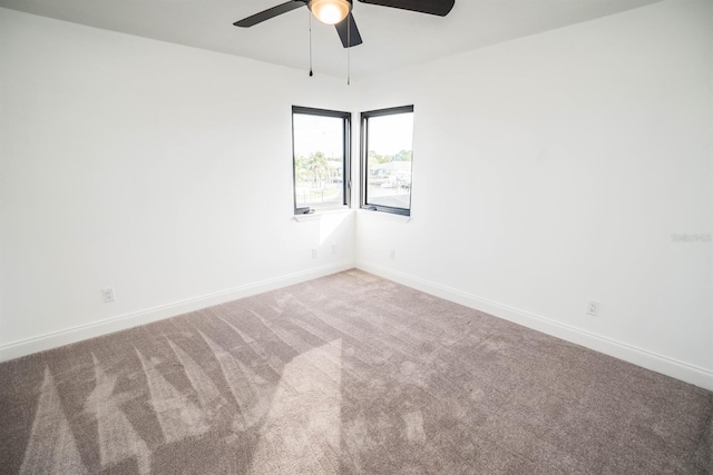 carpeted spare room with ceiling fan and baseboards