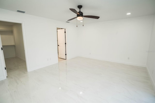 unfurnished bedroom featuring a walk in closet, baseboards, ceiling fan, recessed lighting, and light marble finish flooring