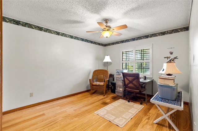 office featuring a textured ceiling, baseboards, a ceiling fan, and wood finished floors