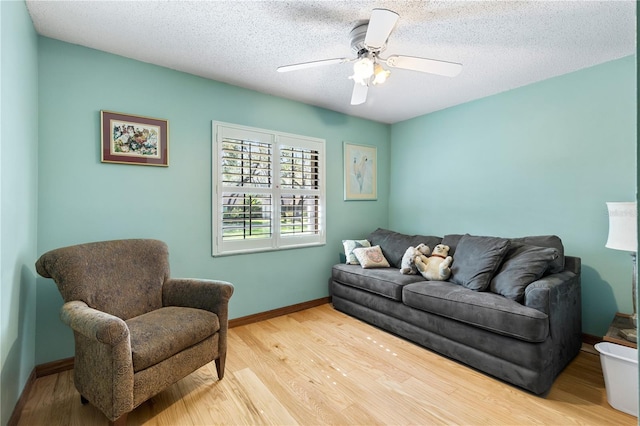 living area with light wood-style floors, baseboards, ceiling fan, and a textured ceiling
