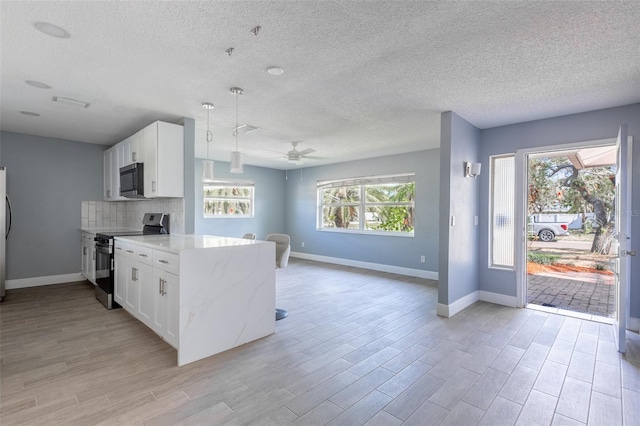 kitchen featuring stainless steel appliances, a ceiling fan, baseboards, and open floor plan