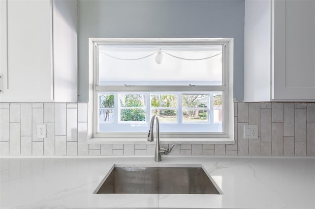 kitchen featuring backsplash, a sink, and white cabinetry