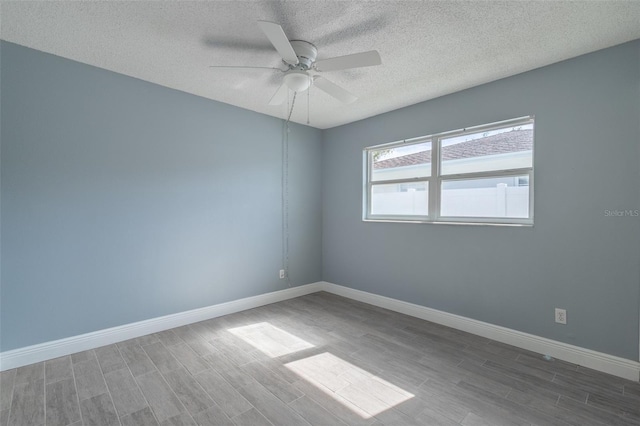 unfurnished room with ceiling fan, baseboards, wood finished floors, and a textured ceiling