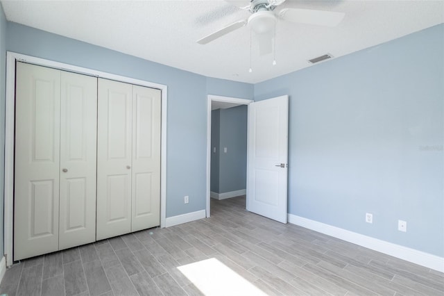 unfurnished bedroom featuring wood tiled floor, baseboards, visible vents, and a closet