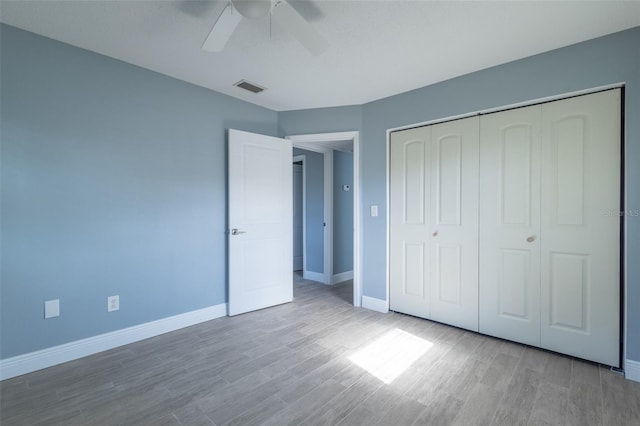 unfurnished bedroom with wood finished floors, a closet, ceiling fan, baseboards, and visible vents