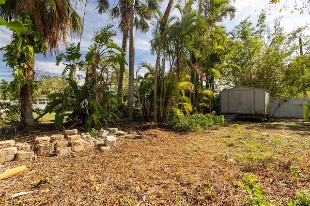 view of yard featuring fence, an outbuilding, and a shed