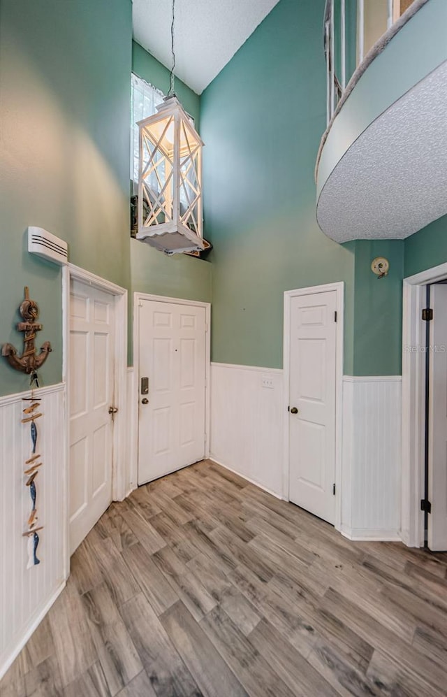 678 Greenglen Ln, Palm Harbor, FL 34684 - foyer with high vaulted ceiling, a wainscoted wall, wood finished floors, and a textured ceiling