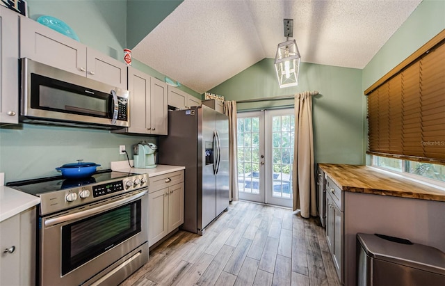 678 Greenglen Ln, Palm Harbor, FL 34684 - kitchen with appliances with stainless steel finishes, light wood-type flooring, a textured ceiling, french doors, and lofted ceiling