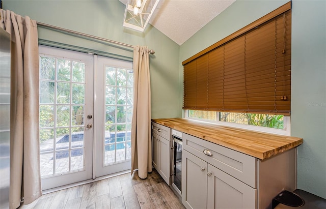 678 Greenglen Ln, Palm Harbor, FL 34684 - kitchen featuring butcher block countertops, french doors, light wood-style floors, beverage cooler, and vaulted ceiling