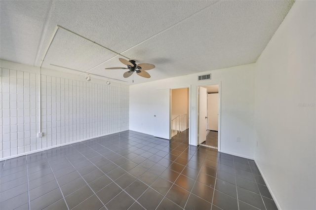 2424 W Tampa Bay Blvd Unit I202, Tampa, FL 33607 - spare room featuring ceiling fan, dark tile patterned floors, a textured ceiling, and baseboards