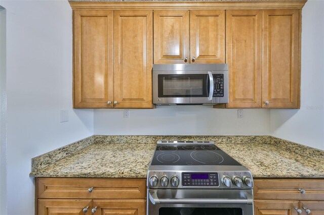 2424 W Tampa Bay Blvd Unit I202, Tampa, FL 33607 - kitchen featuring stainless steel appliances, brown cabinets, and light stone counters