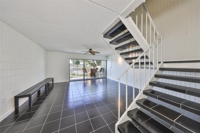 2424 W Tampa Bay Blvd Unit I202, Tampa, FL 33607 - staircase with a ceiling fan, tile patterned floors, tile walls, baseboards, and a textured ceiling