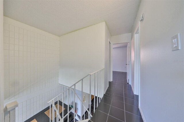 2424 W Tampa Bay Blvd Unit I202, Tampa, FL 33607 - hall featuring an upstairs landing, dark tile patterned floors, and a textured ceiling