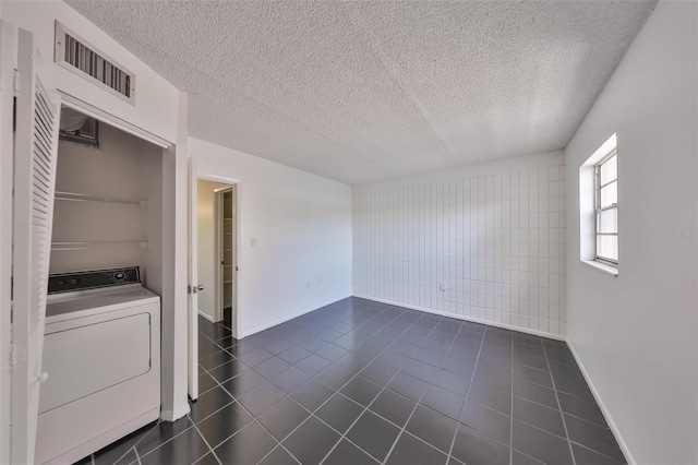 2424 W Tampa Bay Blvd Unit I202, Tampa, FL 33607 - laundry area featuring washer / dryer, a textured ceiling, dark tile patterned flooring, and baseboards