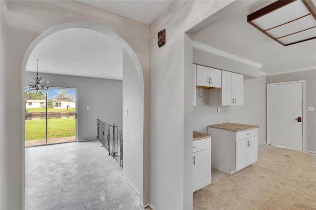 814 Seabreeze Dr, Ruskin, FL 33570 - kitchen featuring arched walkways, white cabinets, a chandelier, a textured ceiling, and crown molding
