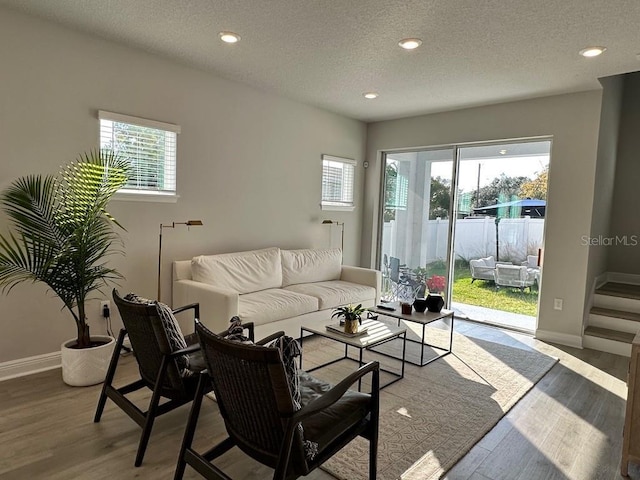 living room with plenty of natural light, wood finished floors, baseboards, a textured ceiling, and recessed lighting