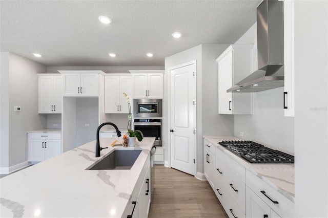 1311 S Moody Ave Unit 1, Tampa, FL 33629 - kitchen featuring stainless steel appliances, wall chimney range hood, light wood-type flooring, white cabinets, and recessed lighting