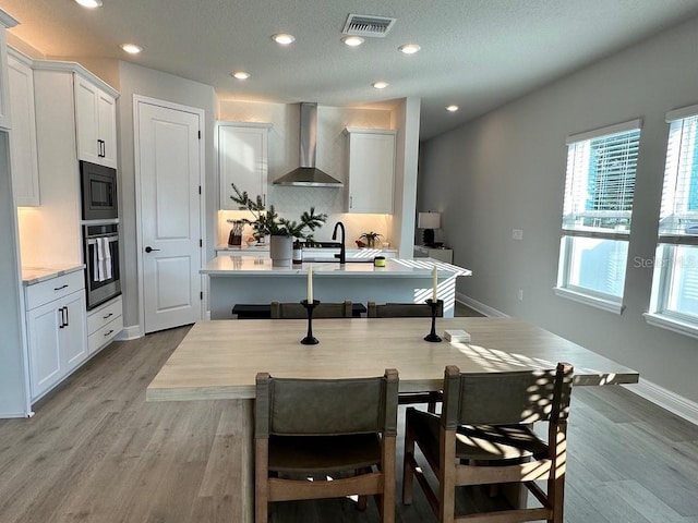 1311 S Moody Ave Unit 1, Tampa, FL 33629 - kitchen featuring wall chimney range hood, stainless steel oven, decorative backsplash, an island with sink, and black microwave