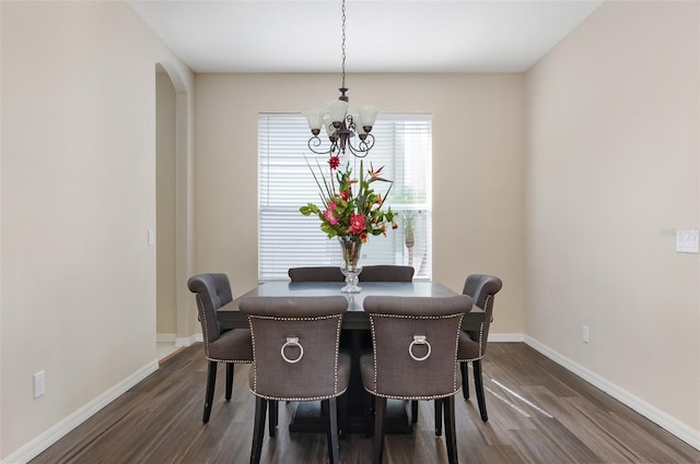 dining area with a chandelier, dark wood finished floors, baseboards, and arched walkways