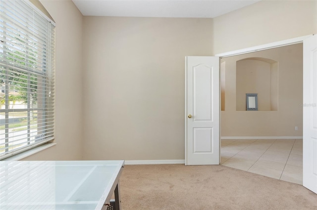 spare room with healthy amount of natural light, carpet, tile patterned floors, and baseboards