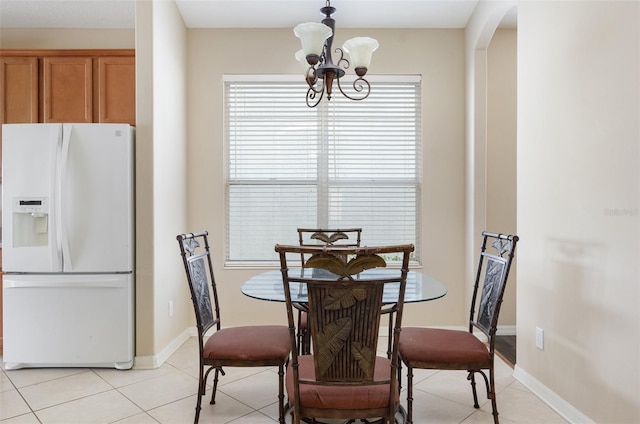 dining room featuring a chandelier, arched walkways, light tile patterned flooring, and baseboards